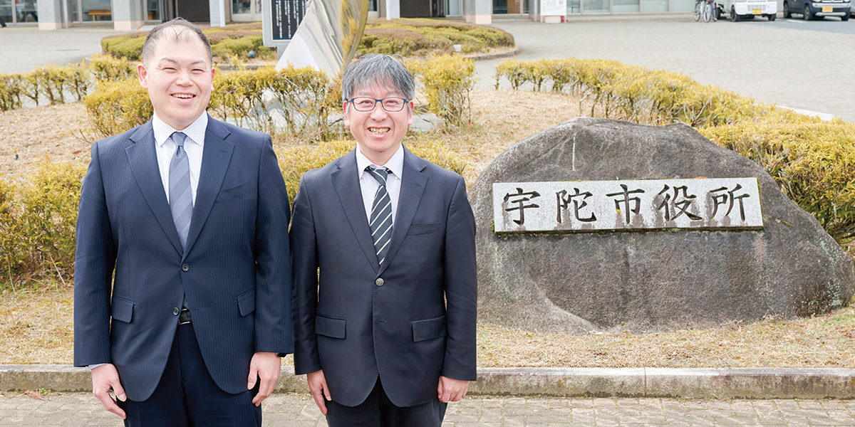 宇陀市役所をバックに、市長公室 秘書広報情報課 課長補佐 末廣智也氏と市長公室 秘書広報情報課 主幹・DX推進室長 山岡茂之氏